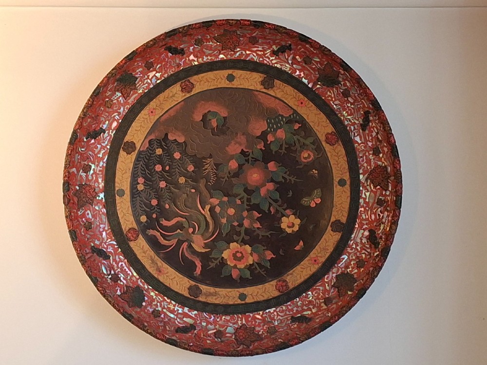 A circular Japanese Meiji period Totai porcelain charger decorated with a central Ho-o phoenix bird amidst floral sprays, framed by an intricate carved cinnabar lacquer border inlaid with mother-of-pearl. View VI