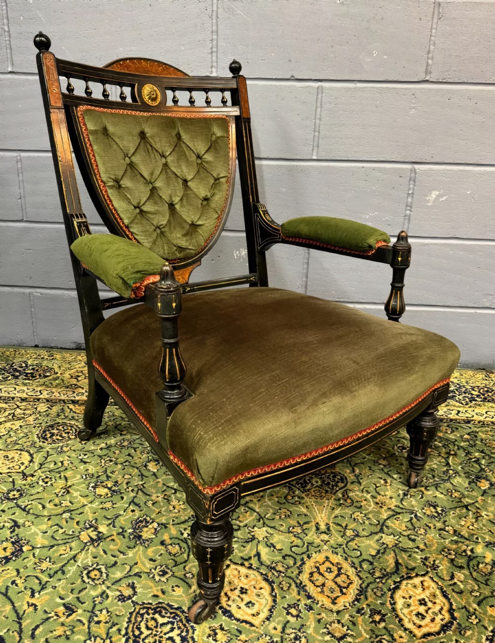 An ebonised Aesthetic Movement salon suite comprising a button-tufted olive green velvet sofa and two matching armchairs with turned spindles and marquetry details. View XIII