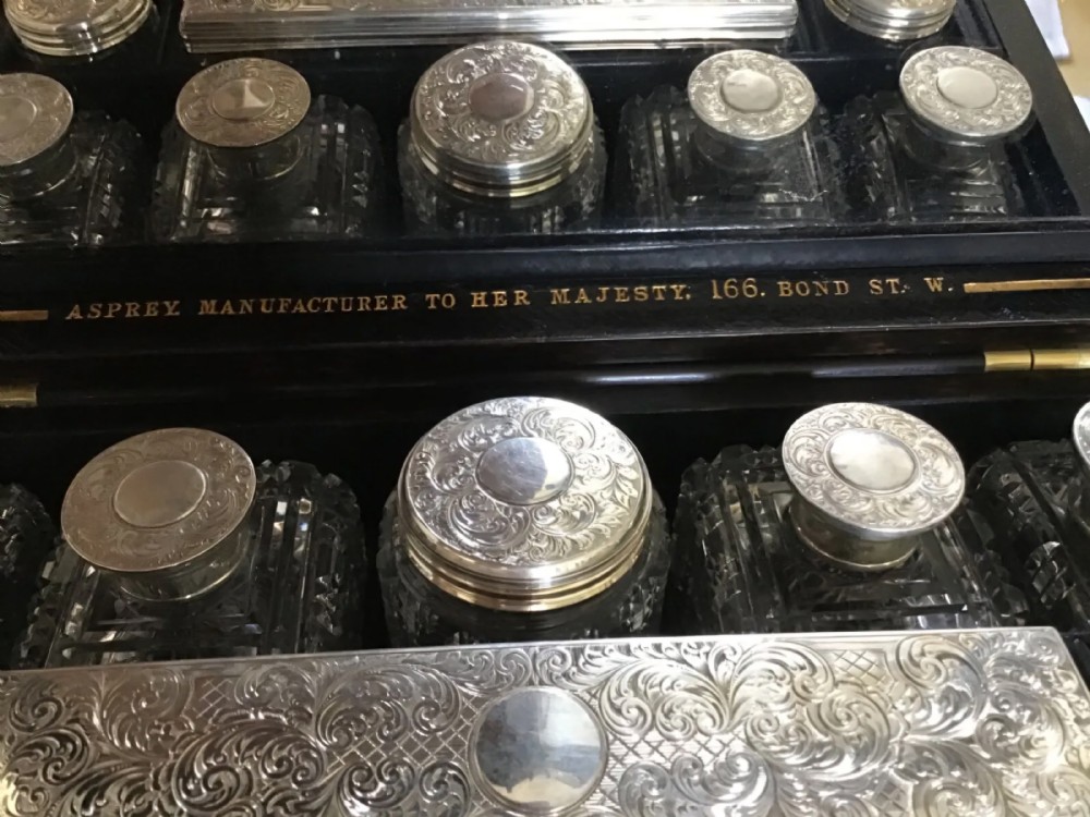 An open Victorian coromandel wood vanity case featuring an interior mirror lid, velvet-lined compartments, silver-topped crystal bottles, and engraved silver containers. View VIII
