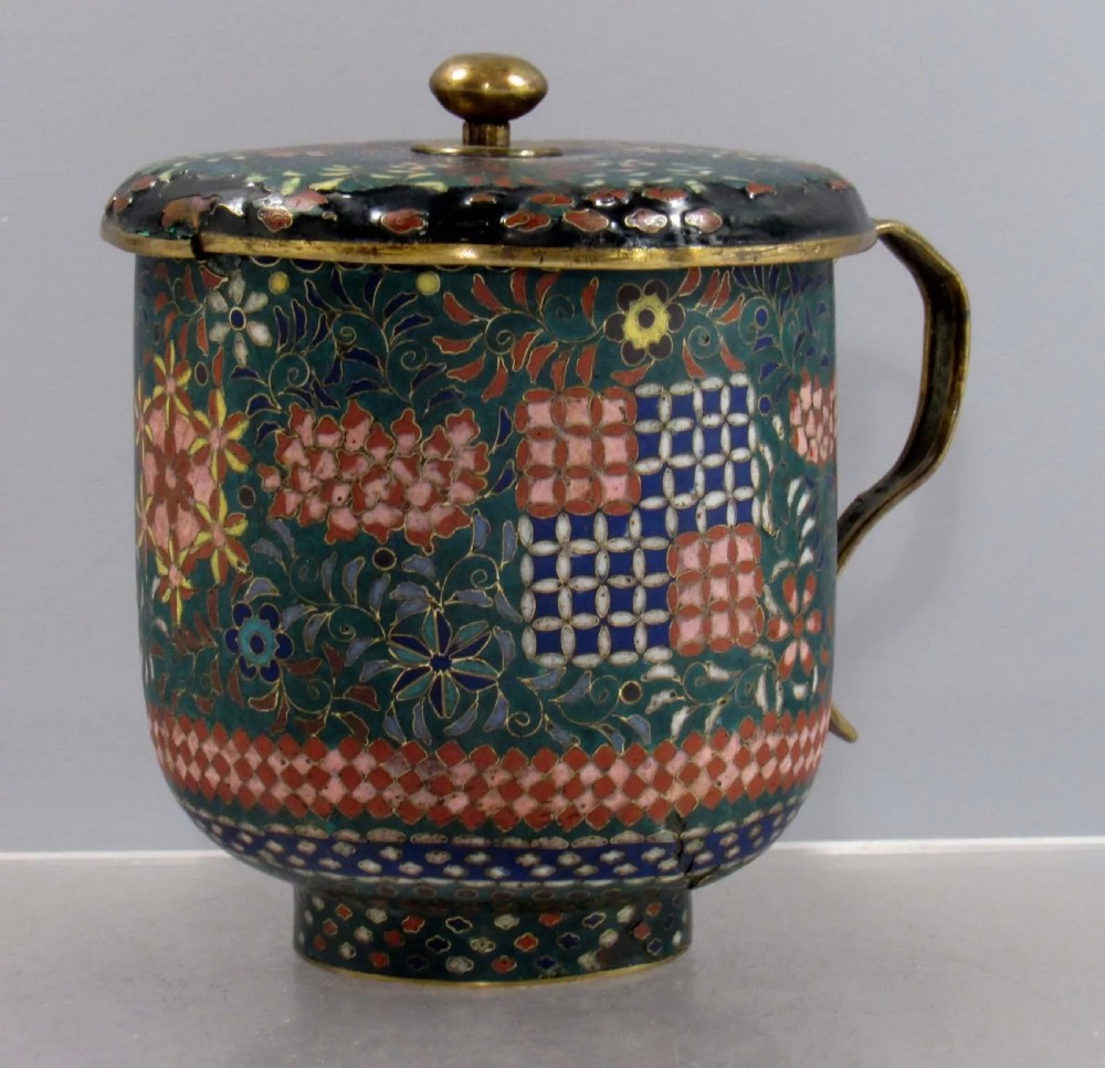 A late Edo period Japanese cloisonne enamel lidded mug featuring green, pink, and blue floral and geometric patterns with brass fittings.