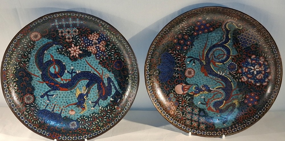 A pair of circular Japanese cloisonne enamel dishes featuring blue dragon motifs on turquoise patterned grounds with decorative borders.