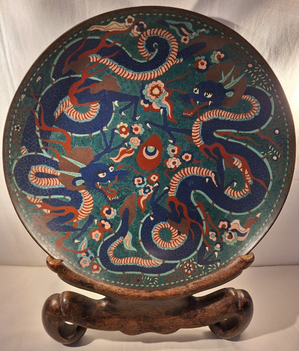 A large circular Japanese cloisonne enamel charger depicting blue dragons with red accents against a teal ground.