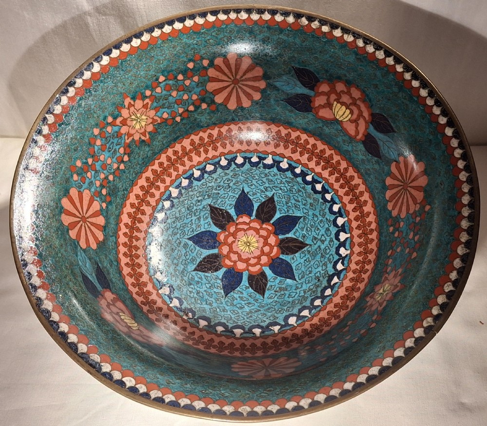 A circular Japanese cloisonne enamel bowl featuring a flared rim and floral pattern band against a bright turquoise ground. View II