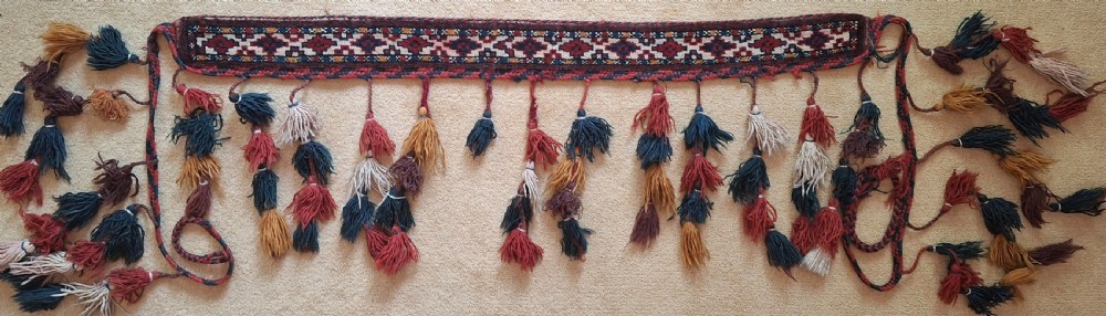 A pair of handwoven wool Turkoman camel neck trappings featuring geometric red and cream bands trimmed with dense multicoloured tassels. View III