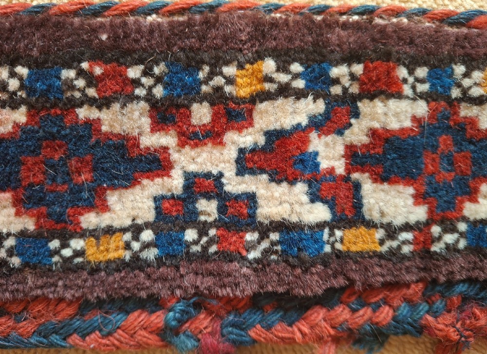 A pair of handwoven wool Turkoman camel neck trappings featuring geometric red and cream bands trimmed with dense multicoloured tassels. View VI