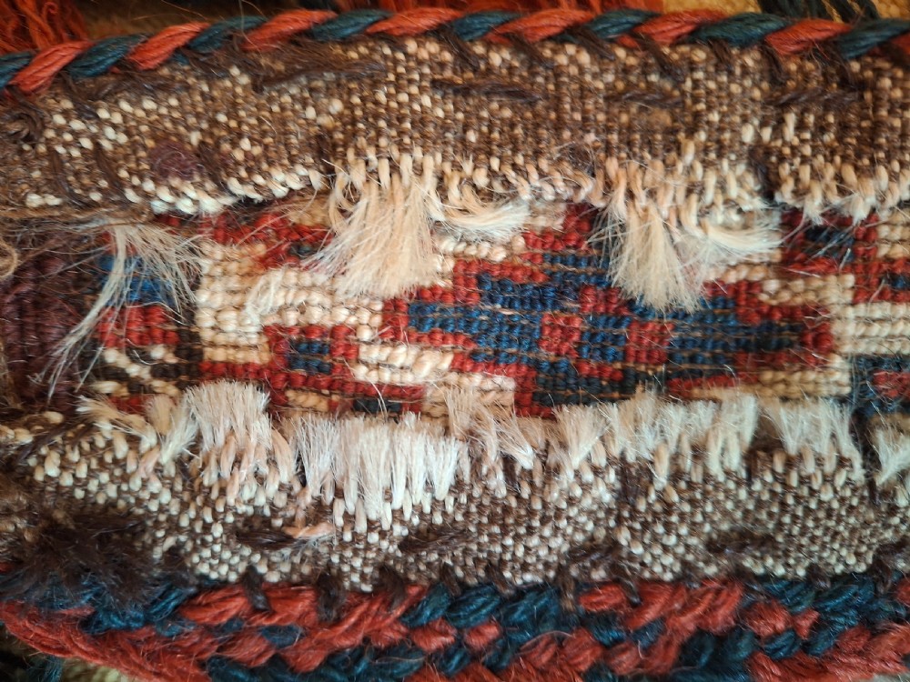 A pair of handwoven wool Turkoman camel neck trappings featuring geometric red and cream bands trimmed with dense multicoloured tassels. View IX