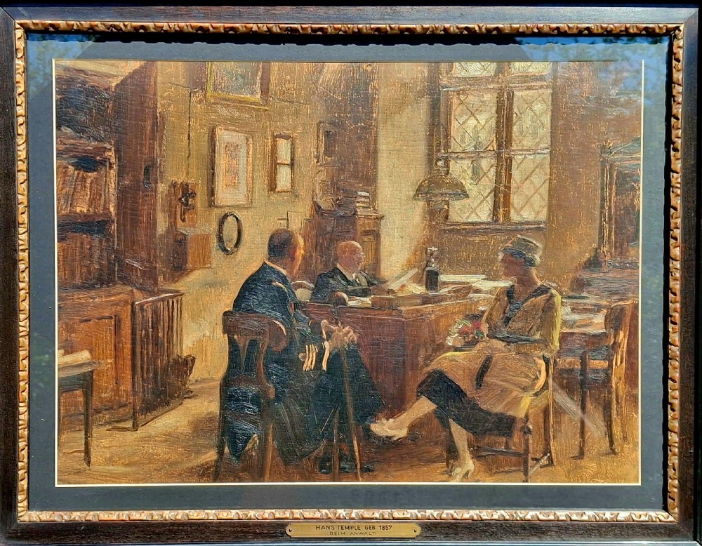 A framed early 20th-century oil painting on panel depicting three figures seated inside a sunlit interior room.