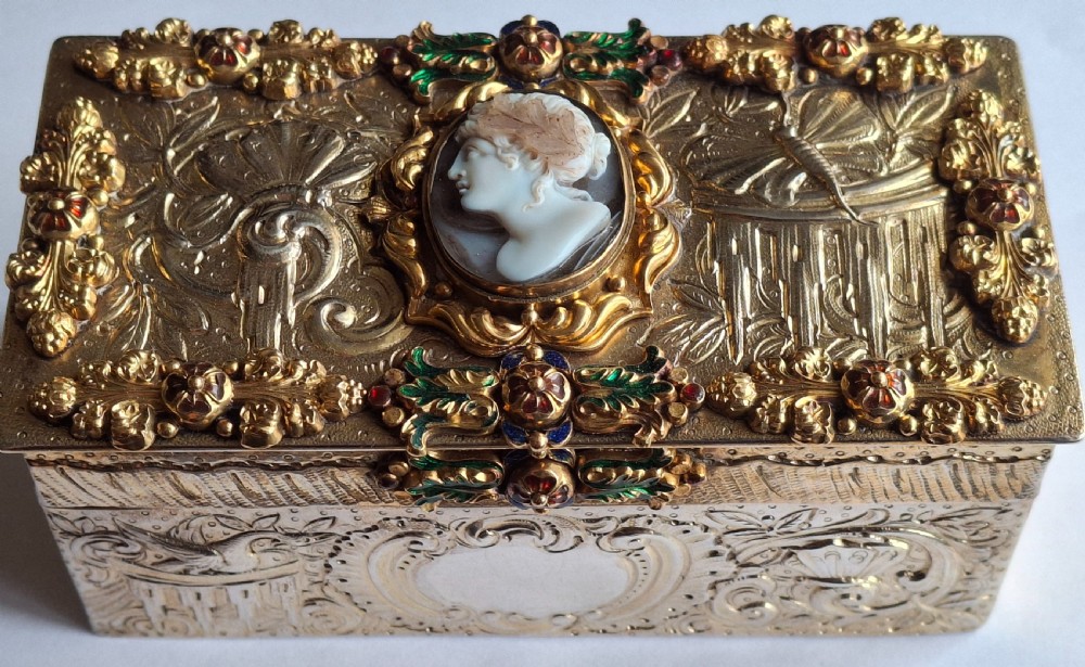 A rectangular silver-gilt Renaissance Revival table box featuring intricate chased relief, polychrome enamel appliques, and a central carved profile cameo.