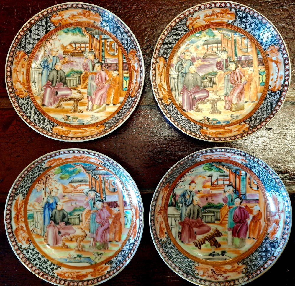 A set of four circular Chinese export porcelain saucers hand-painted with figural scenes inside pavilions framed by geometric borders in orange and polychrome enamels.