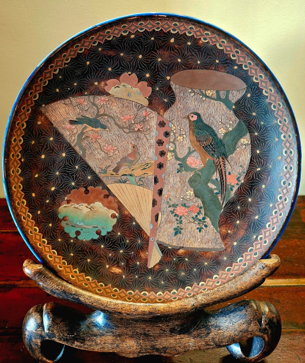 A Japanese Totai Shippo porcelain charger featuring birds, blossoms, and fan motifs against a brown tree-bark textured enamel surface.