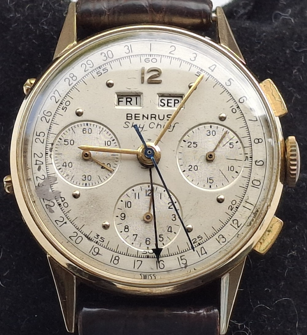A 1940s Benrus Sky Chief gold chronograph wristwatch with a triple date display and dark brown leather strap.