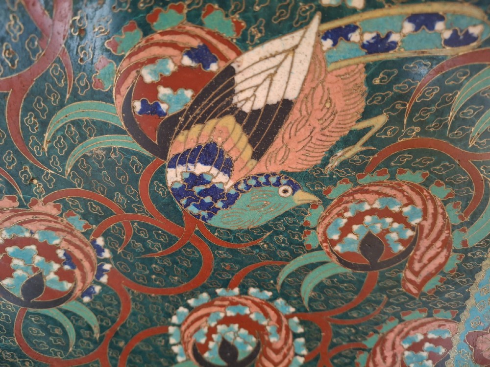 A circular Japanese cloisonne enamel charger decorated with a central bird, scrollwork tendrils, and floral mon patterns in teal green, pink, and terracotta red. View IX
