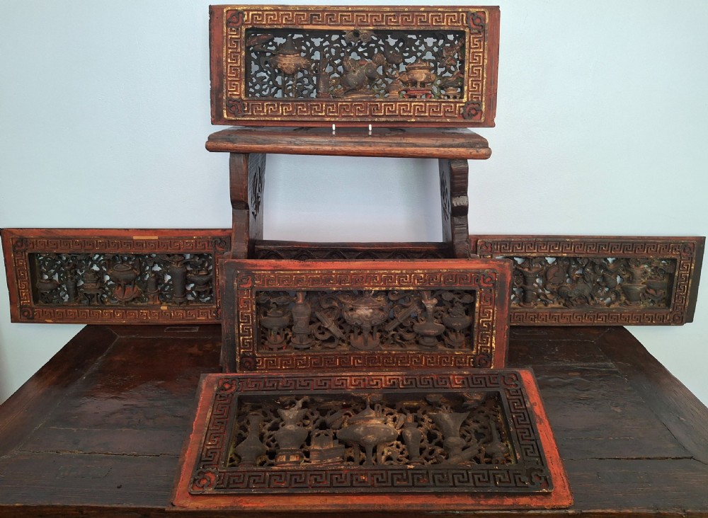A set of five rectangular Qing Dynasty carved wooden panels featuring openwork depictions of scholars objects with red lacquer frames and gilded accents.