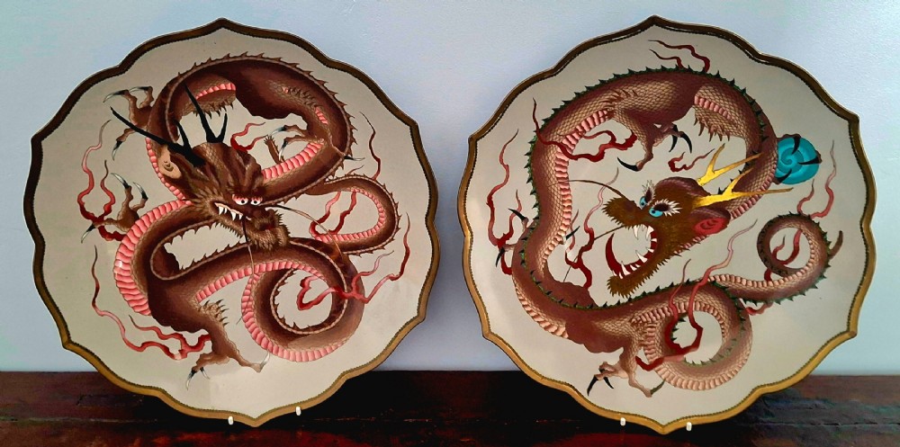 A pair of Japanese scalloped cloisonne chargers decorated with coiled dragon motifs against a cream background.