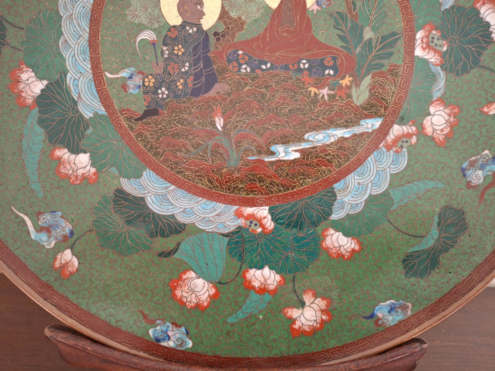 A circular Meiji period Japanese cloisonne enamel charger featuring central haloed figures surrounded by a lotus pattern on a green background. View IV