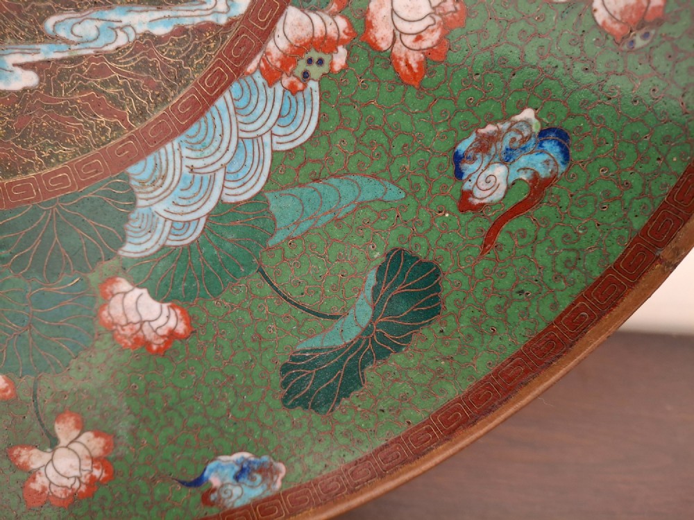 A circular Meiji period Japanese cloisonne enamel charger featuring central haloed figures surrounded by a lotus pattern on a green background. View VII