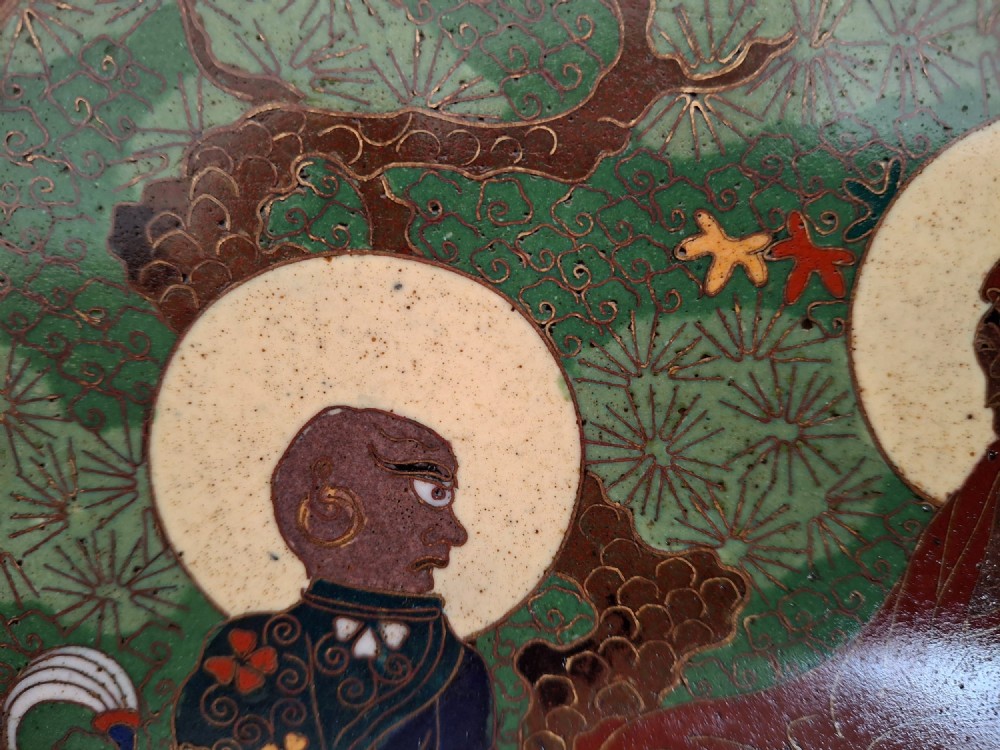 A circular Meiji period Japanese cloisonne enamel charger featuring central haloed figures surrounded by a lotus pattern on a green background. View IX