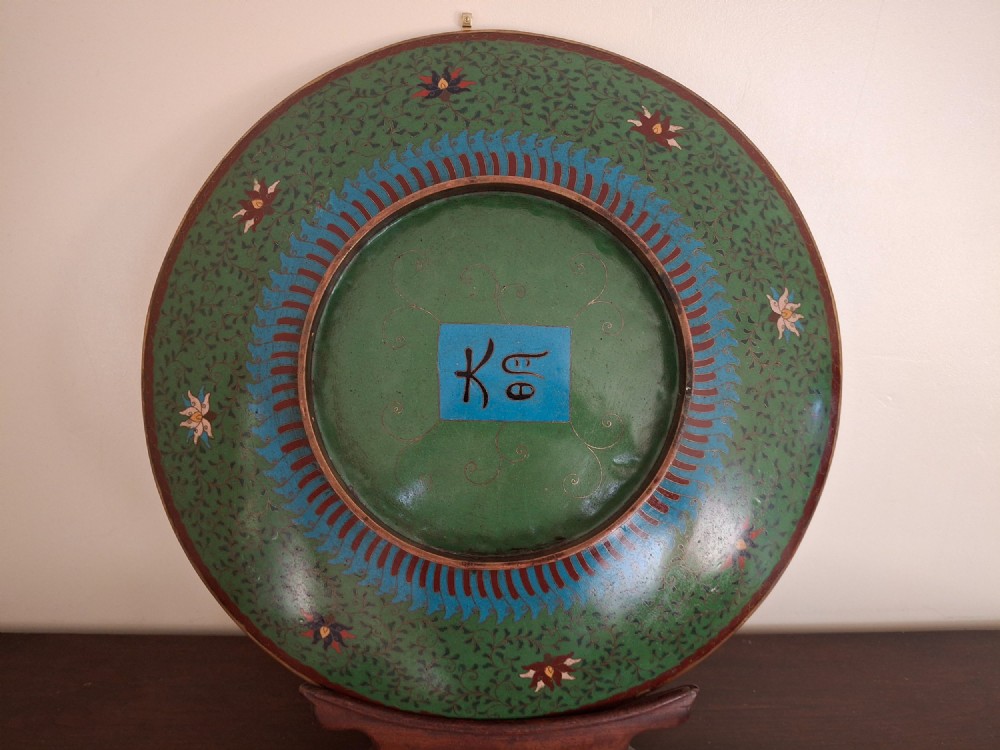 A circular Meiji period Japanese cloisonne enamel charger featuring central haloed figures surrounded by a lotus pattern on a green background. View XI