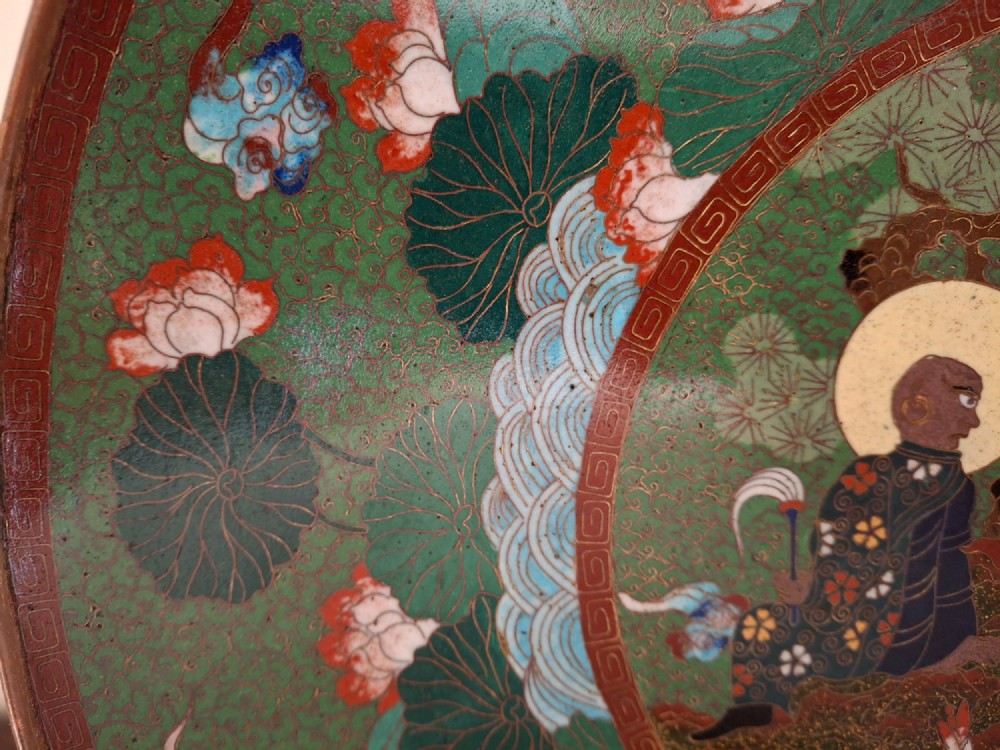 A circular Meiji period Japanese cloisonne enamel charger featuring central haloed figures surrounded by a lotus pattern on a green background. View XII