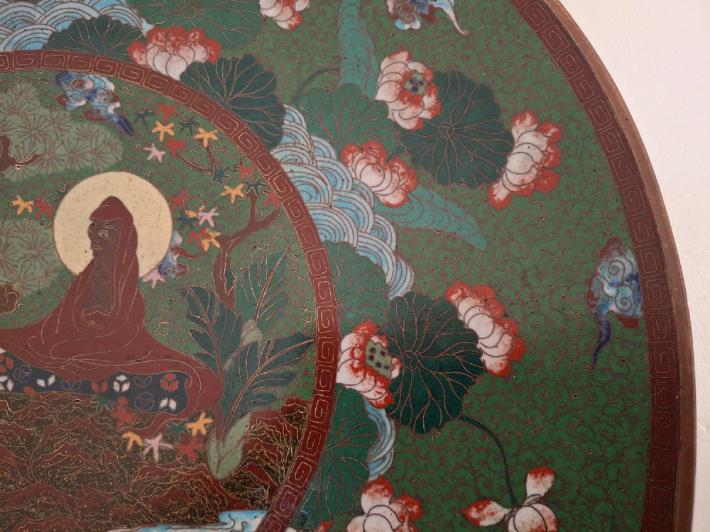 A circular Meiji period Japanese cloisonne enamel charger featuring central haloed figures surrounded by a lotus pattern on a green background. View XIII