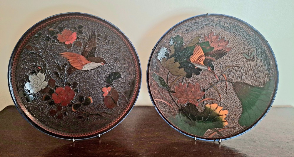 A pair of circular Japanese Totai Shippo porcelain plates depicting birds, lotus flowers, and peonies in polychrome enamel against a textured brown tree bark effect ground.
