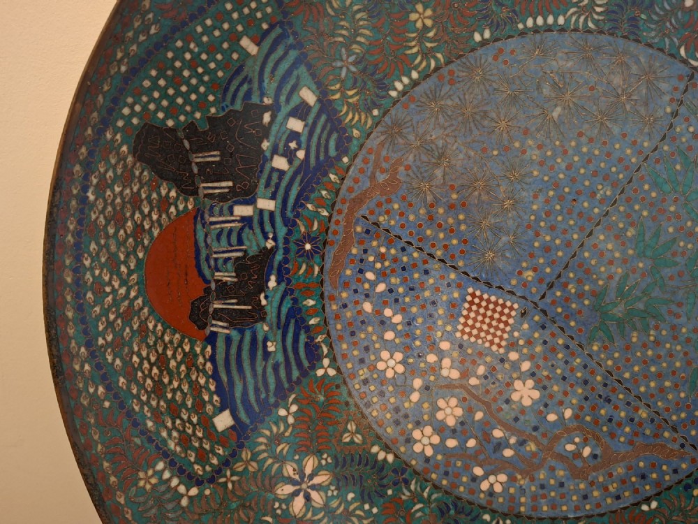 A circular Japanese cloisonne enamel charger decorated with geometric reserves, floral patterns, foliage, and bird motifs in blue, green, and terracotta tones. View IV