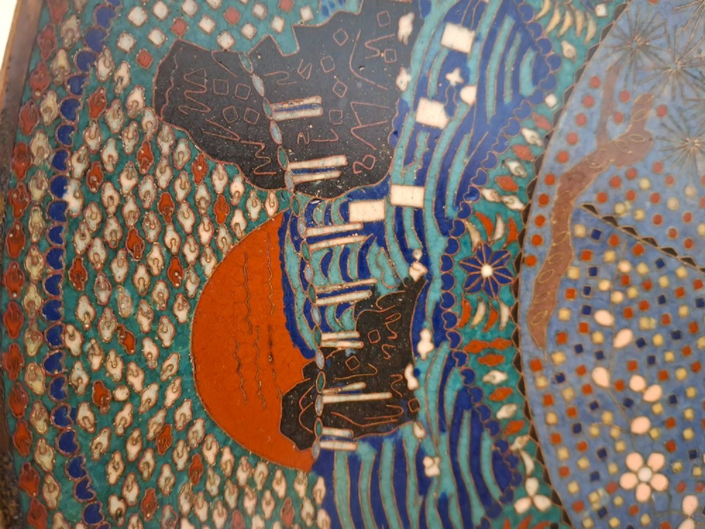 A circular Japanese cloisonne enamel charger decorated with geometric reserves, floral patterns, foliage, and bird motifs in blue, green, and terracotta tones. View IX