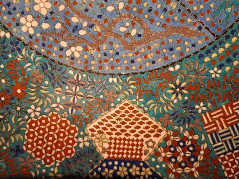 A circular Japanese cloisonne enamel charger decorated with geometric reserves, floral patterns, foliage, and bird motifs in blue, green, and terracotta tones. View X