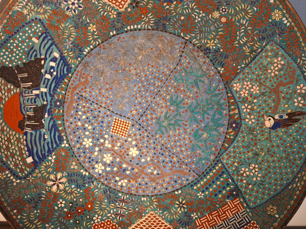 A circular Japanese cloisonne enamel charger decorated with geometric reserves, floral patterns, foliage, and bird motifs in blue, green, and terracotta tones. View XI