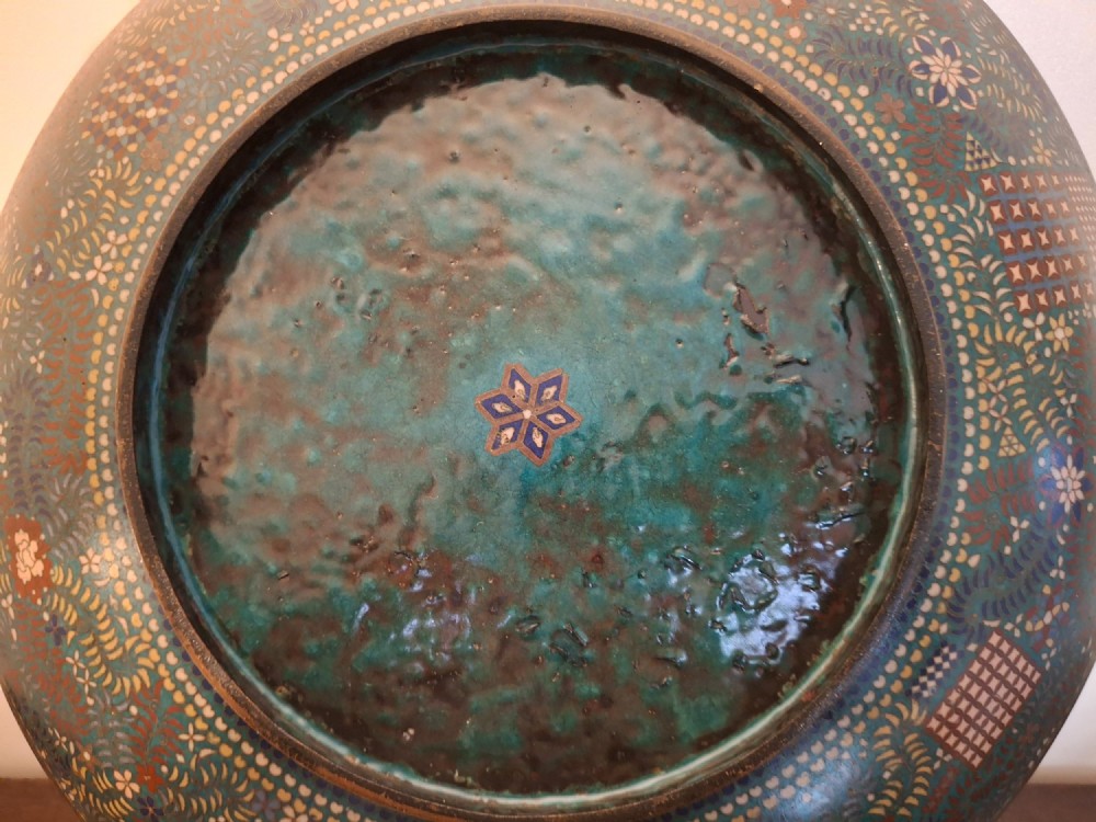 A circular Japanese cloisonne enamel charger decorated with geometric reserves, floral patterns, foliage, and bird motifs in blue, green, and terracotta tones. View XII