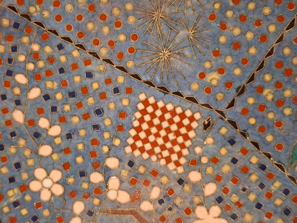 A circular Japanese cloisonne enamel charger decorated with geometric reserves, floral patterns, foliage, and bird motifs in blue, green, and terracotta tones. View II