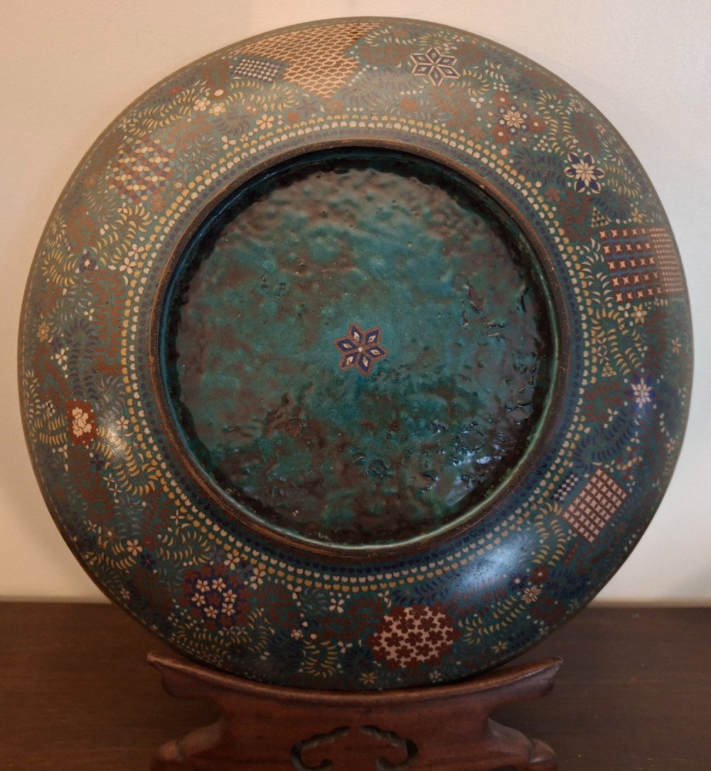A circular Japanese cloisonne enamel charger decorated with geometric reserves, floral patterns, foliage, and bird motifs in blue, green, and terracotta tones. View XIII
