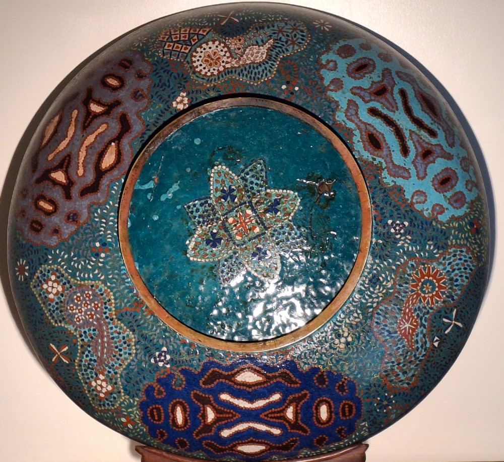 Large circular antique Japanese cloisonne enamel charger featuring a central peony motif surrounded by intricate geometric and floral diaper patterns in teal, blue, and coral hues. View X