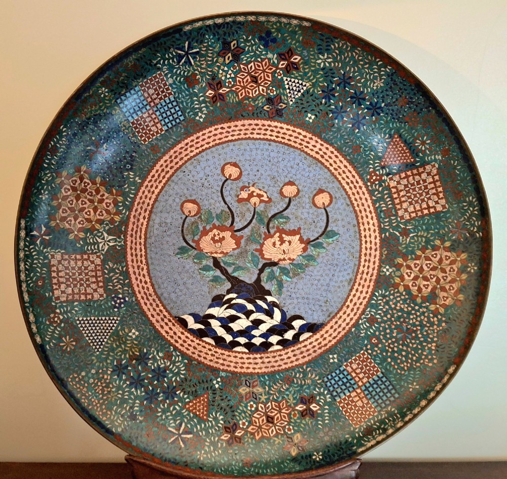 Large circular antique Japanese cloisonne enamel charger featuring a central peony motif surrounded by intricate geometric and floral diaper patterns in teal, blue, and coral hues.