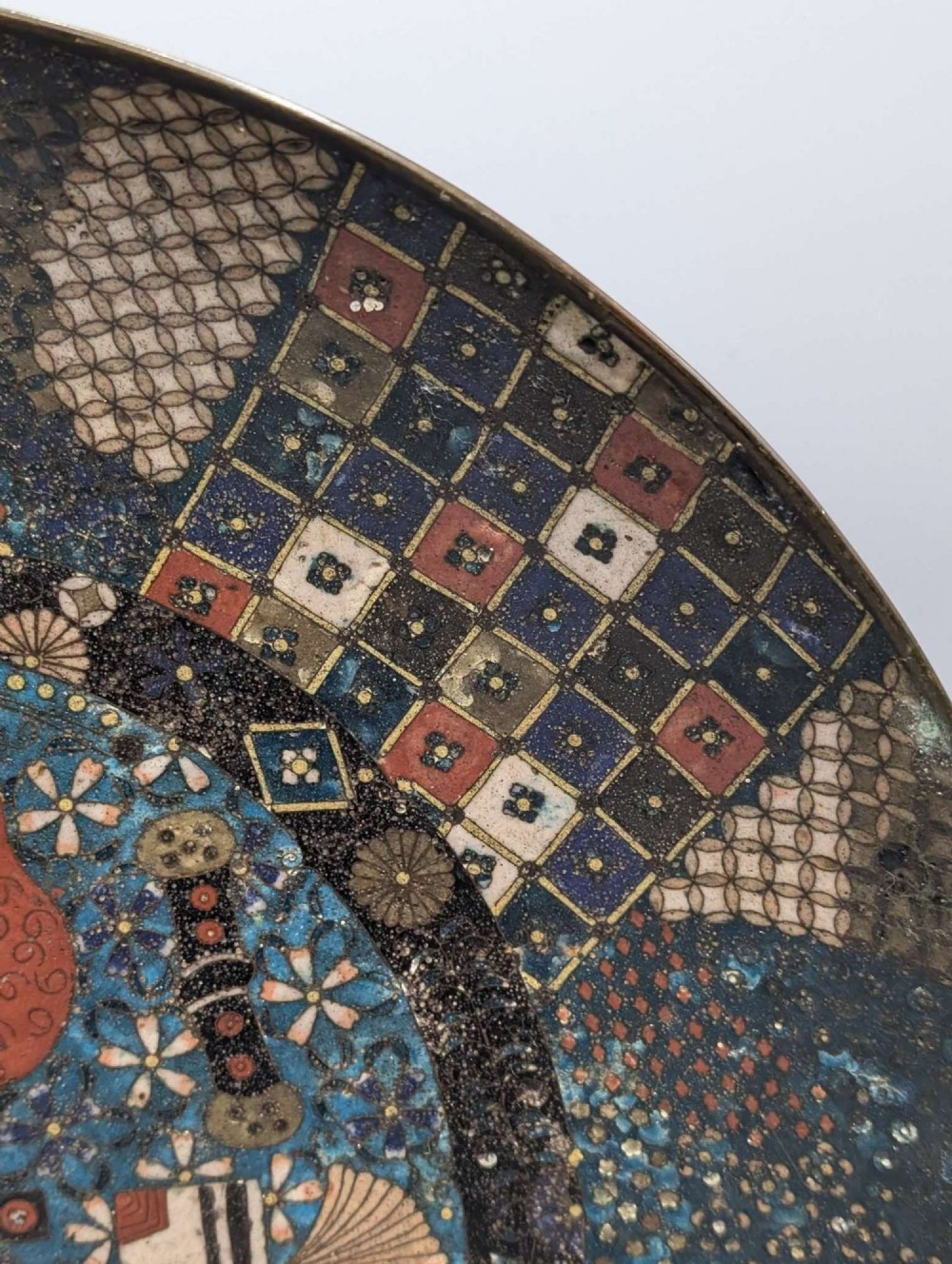 A circular Japanese cloisonne charger featuring a central blue medallion with a red Daruma figure surrounded by detailed geometric and floral patterned borders. View VIII