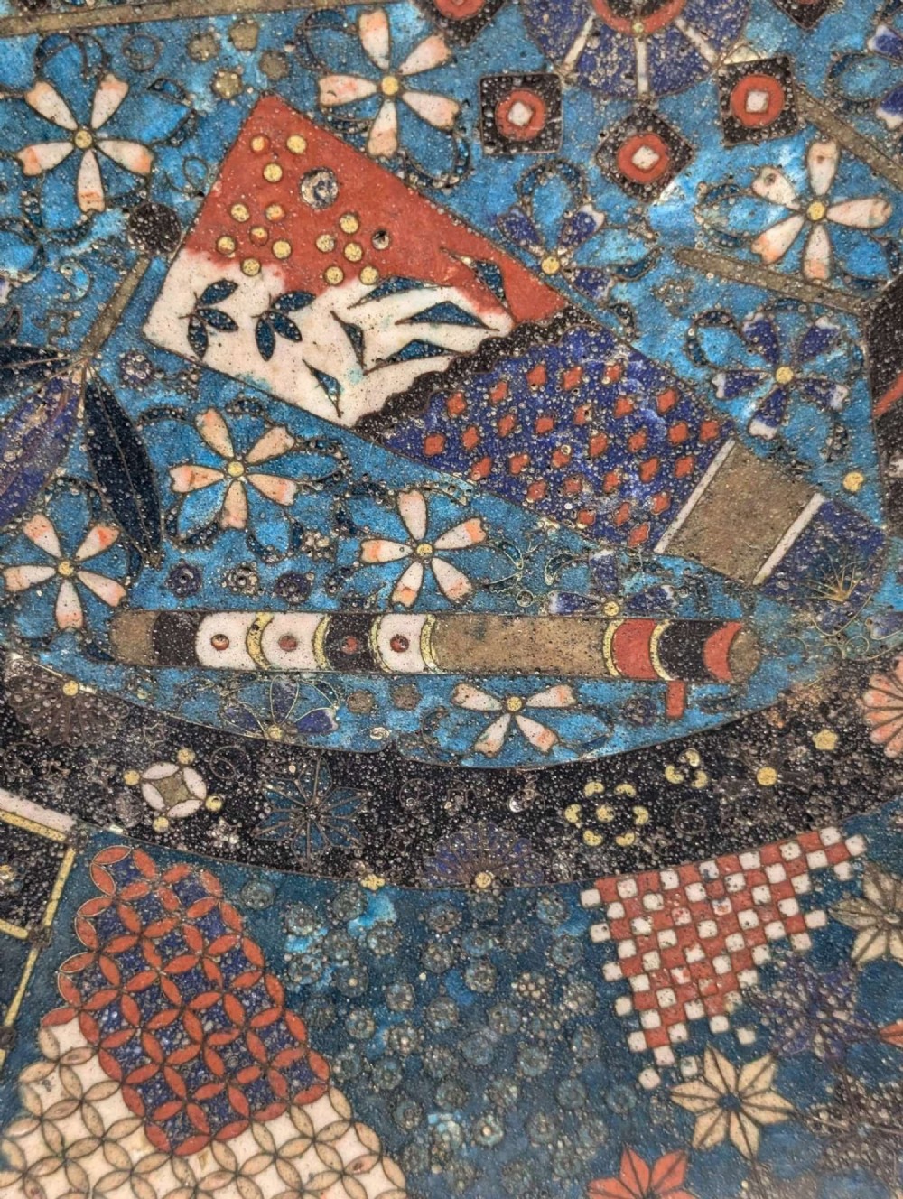 A circular Japanese cloisonne charger featuring a central blue medallion with a red Daruma figure surrounded by detailed geometric and floral patterned borders. View X