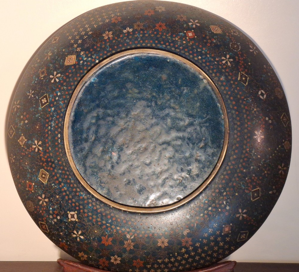 A circular Japanese cloisonne charger featuring a central blue medallion with a red Daruma figure surrounded by detailed geometric and floral patterned borders. View XIV