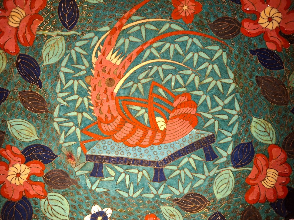 A circular Japanese cloisonne enamel charger displaying an orange shrimp motif surrounded by red flowers on a teal green pattern background. View III