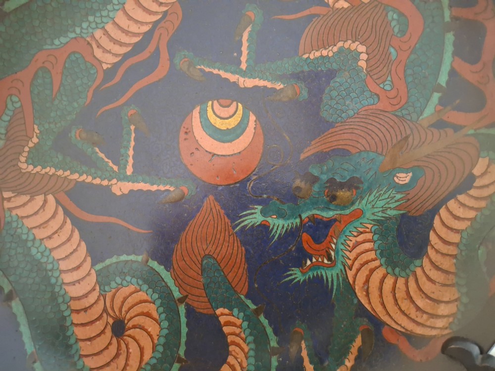 A circular Japanese Meiji period cloisonne enamel charger featuring a green and terracotta coiling dragon surrounding a flaming pearl on a dark blue background. View III