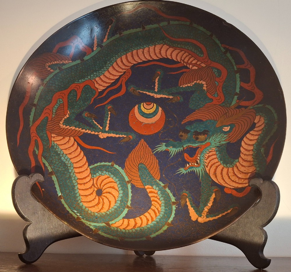 A circular Japanese Meiji period cloisonne enamel charger featuring a green and terracotta coiling dragon surrounding a flaming pearl on a dark blue background. View VI