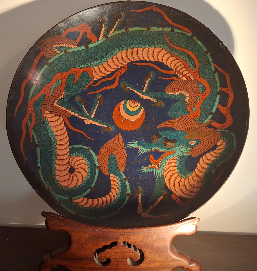 A circular Japanese Meiji period cloisonne enamel charger featuring a green and terracotta coiling dragon surrounding a flaming pearl on a dark blue background. View IX