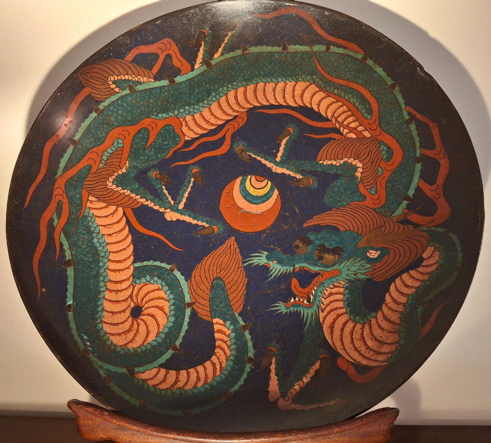 A circular Japanese Meiji period cloisonne enamel charger featuring a green and terracotta coiling dragon surrounding a flaming pearl on a dark blue background. View X