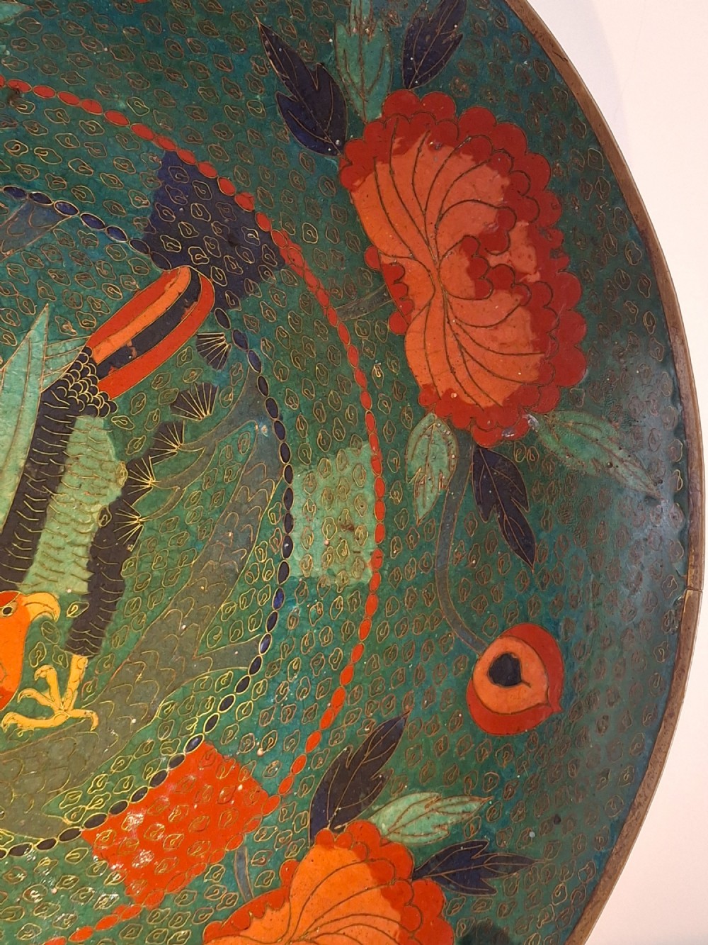 A circular antique Japanese cloisonne charger featuring a central bird motif surrounded by large orange peony blossoms on a green patterned enamel ground. View IX