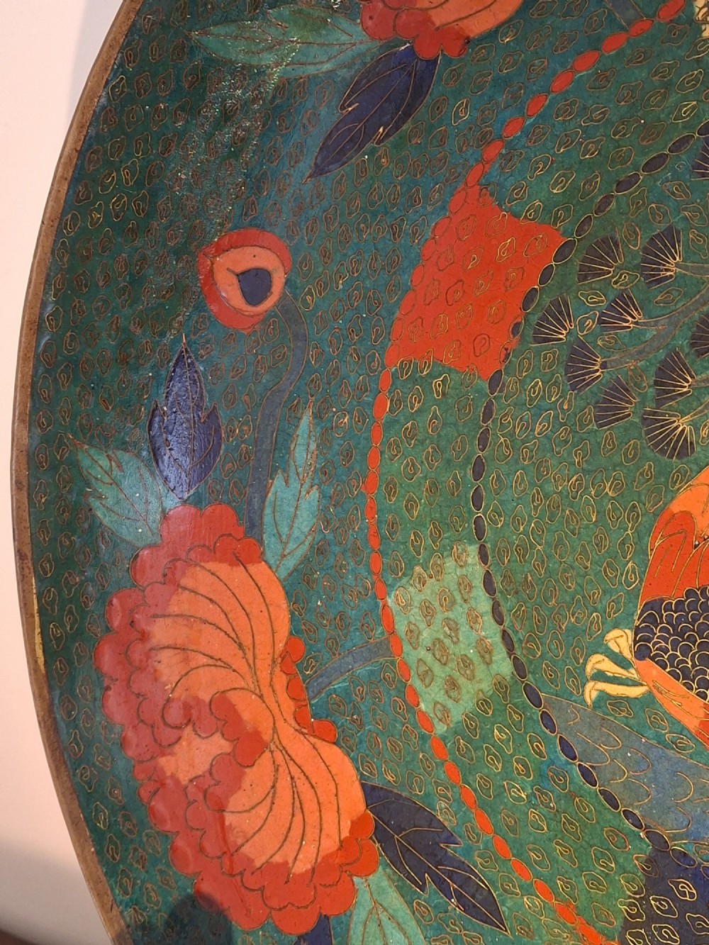 A circular antique Japanese cloisonne charger featuring a central bird motif surrounded by large orange peony blossoms on a green patterned enamel ground. View X
