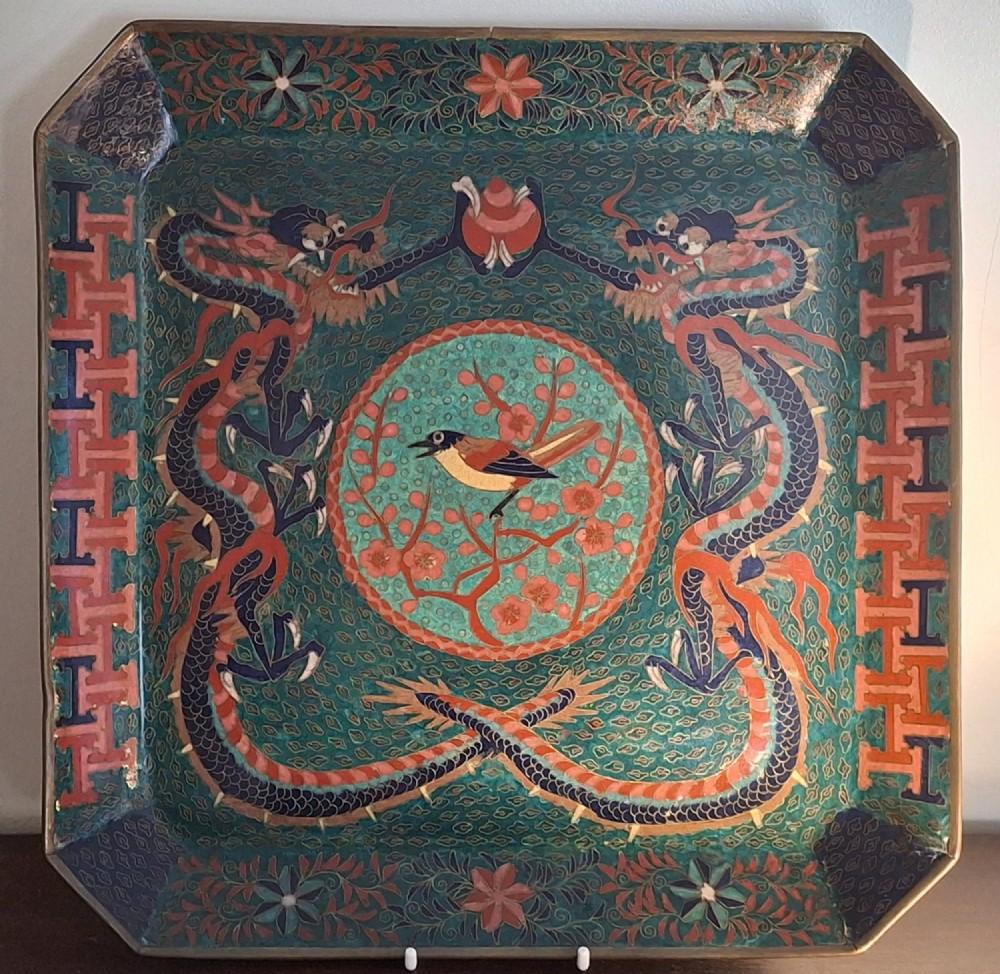 Square Japanese cloisonne enamel tray featuring a central bird motif surrounded by two coiled dragons on a teal patterned ground.