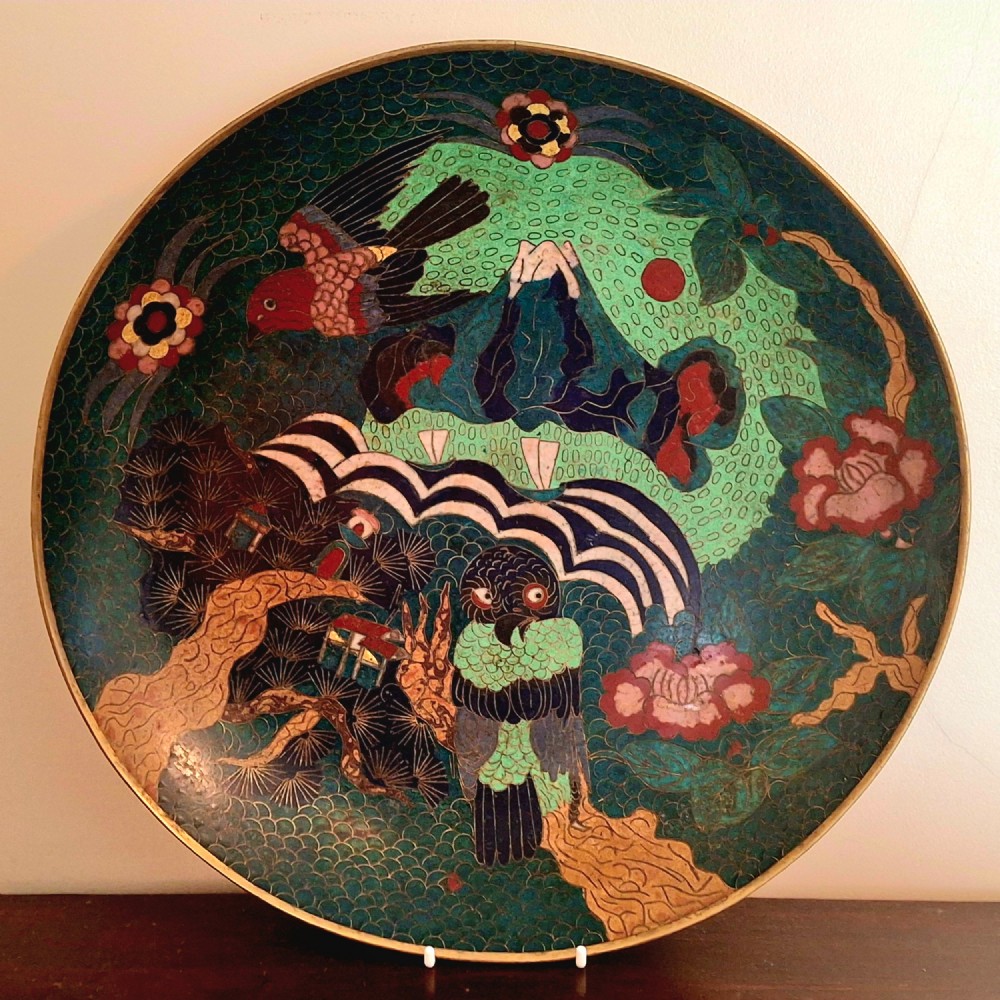 A circular Japanese cloisonne enamel charger featuring an owl, a flying bird, wave patterns, and Mount Fuji against a green ground.