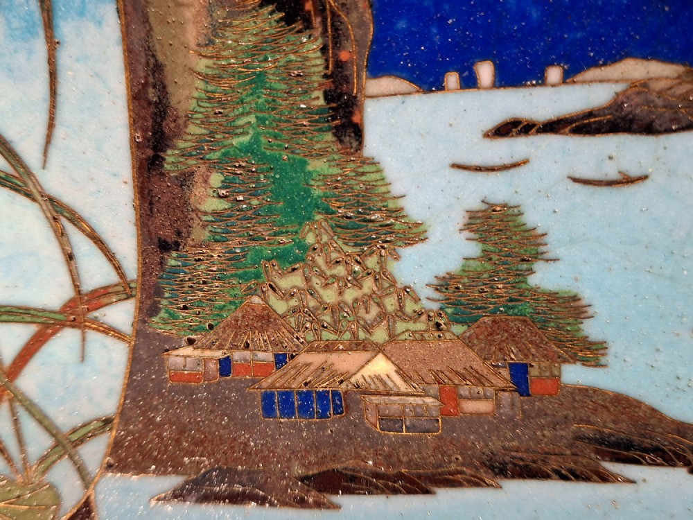 A circular Japanese cloisonne enamel plate featuring geometric patterned borders around asymmetrical panels depicting flora, a bird, and a nocturnal coastal scene. View XII