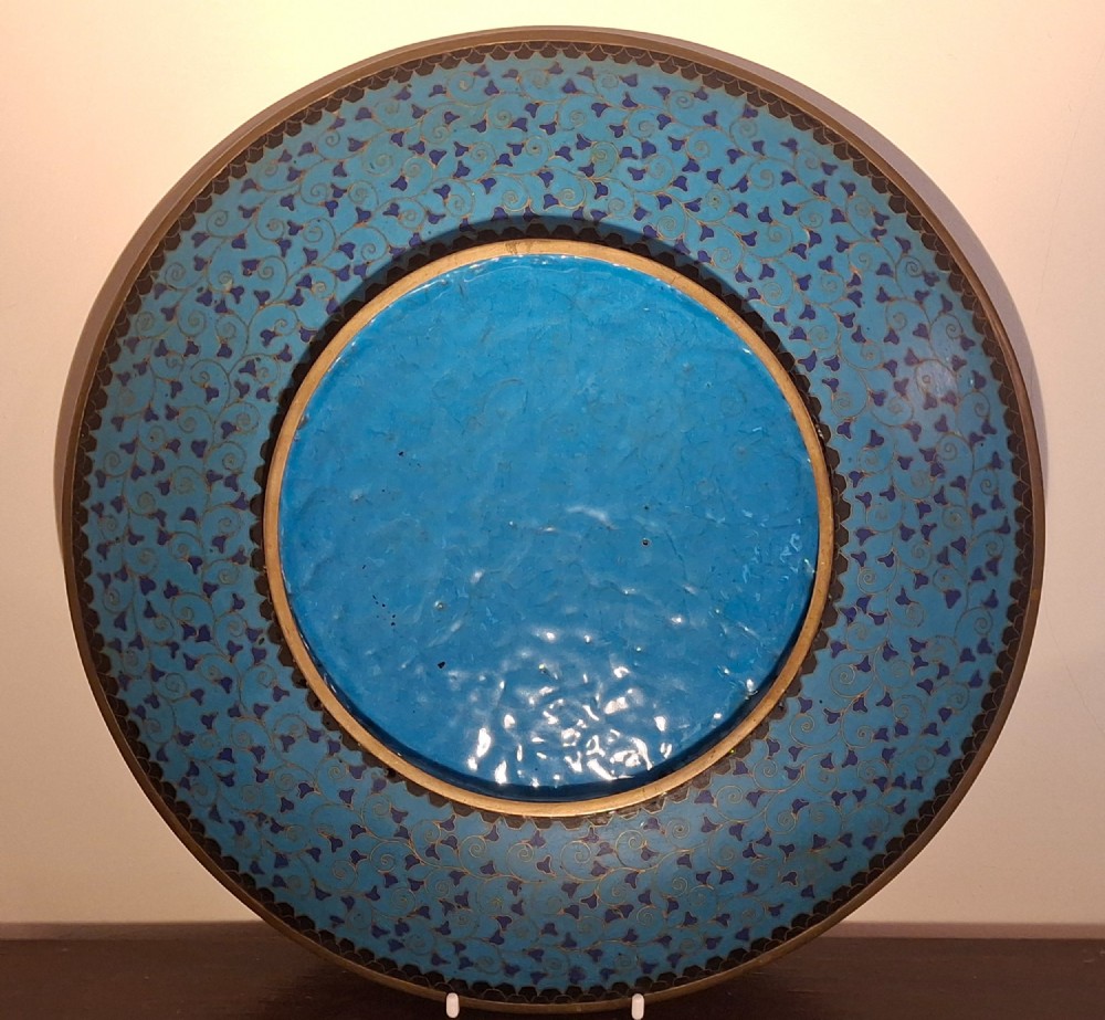 A circular Japanese cloisonne enamel plate featuring geometric patterned borders around asymmetrical panels depicting flora, a bird, and a nocturnal coastal scene. View XIII