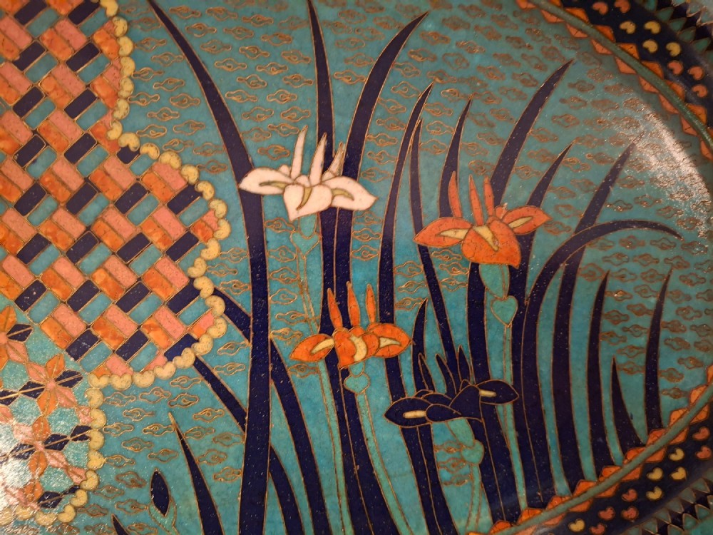 An oval Japanese cloisonne enamel tray featuring a turquoise background decorated with blue and orange iris flowers alongside geometric lattice patterns. View III