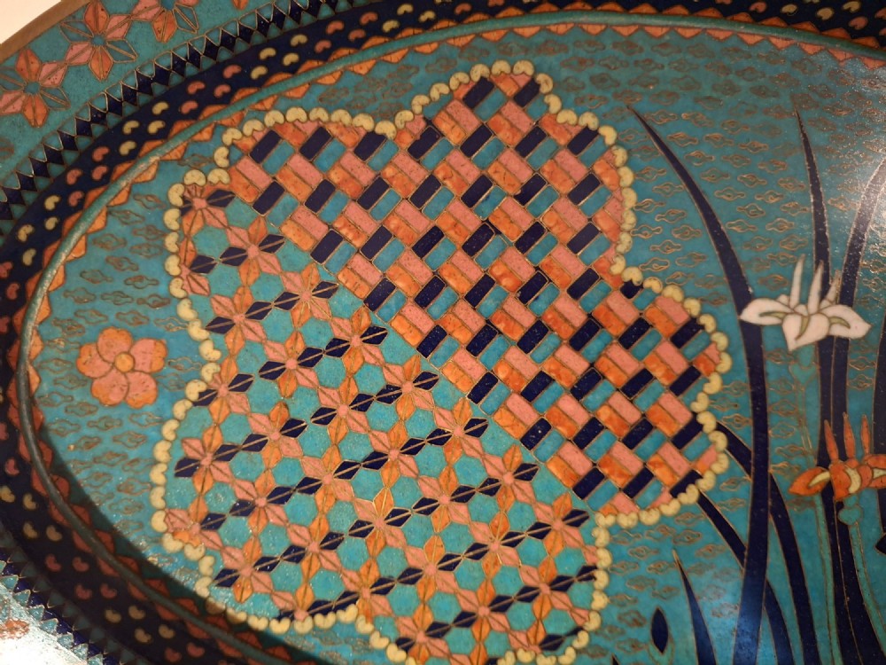 An oval Japanese cloisonne enamel tray featuring a turquoise background decorated with blue and orange iris flowers alongside geometric lattice patterns. View IV